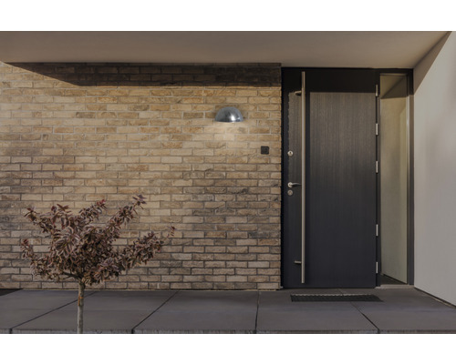 Exteriör av ett hus med en ytterdörr, en utomhuslampa och en tegelvägg