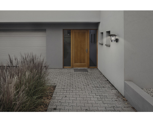 Exteriör av ett modernt hus med garage, ytterdörr, utomhuslampa och växter