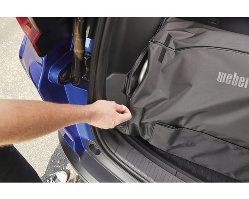 Weber bärväska i bagageutrymmet på en bil med en hand som öppnar dragkedjan.