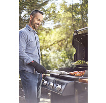 En man grillar kött och grönsaker på en gasolgrill utomhus.