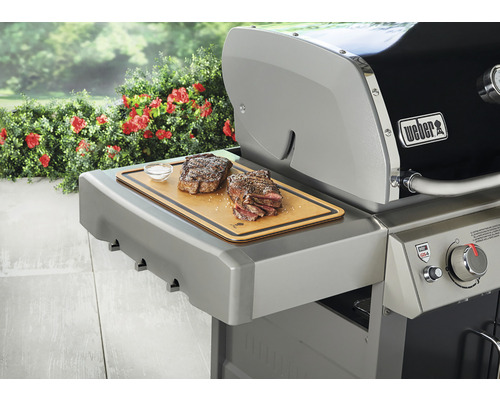 Weber grill med biff och skärbräda på sidobordet