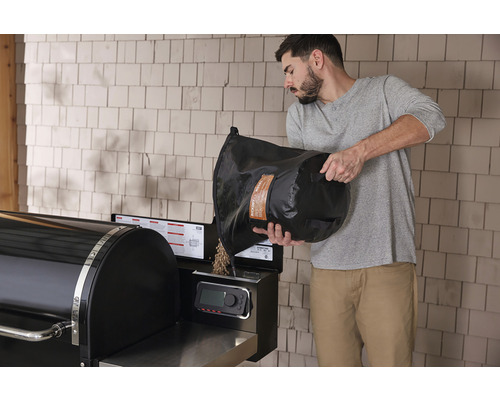 Man fyller träpellets i en pelletgrill