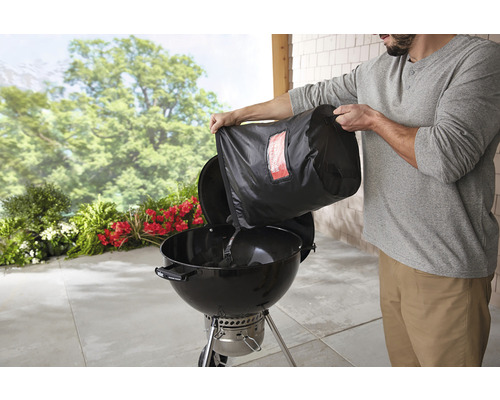 En person häller kol från en påse i en kolgrill.