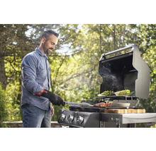 Man grillar kött och grönsaker på en gasolgrill utomhus.