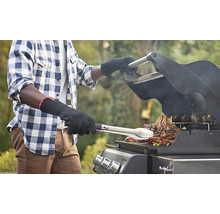 En person grillar kött på en gasolgrill med grillhandskar och grilltång.
