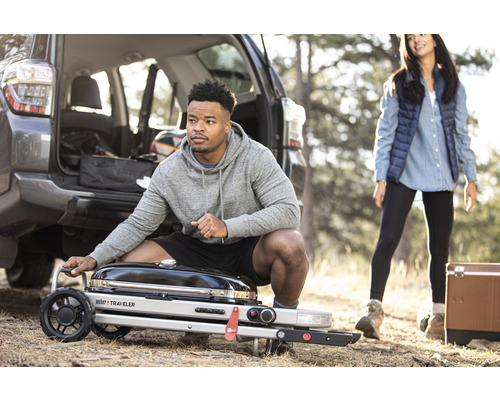 Man sitter bredvid en Weber Traveler-grill utomhus