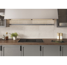 Köksscen med induktionshäll, fläkt och köksredskap på bänkskivan