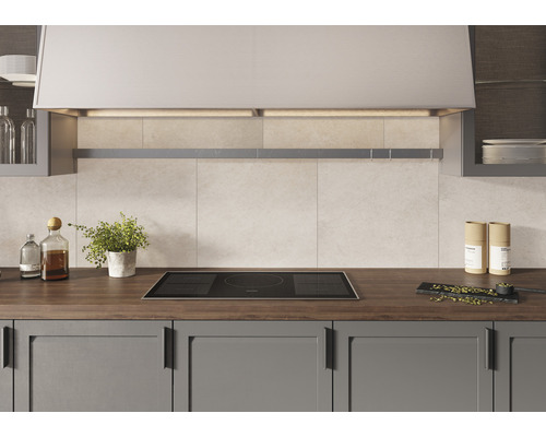 Köksscen med induktionshäll, köksfläkt och köksredskap på en bänkskiva