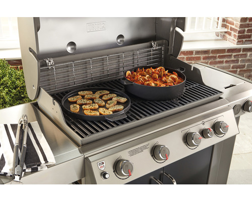 Weber gasolgrill med grillad mat och kokkärl på grillgallret.