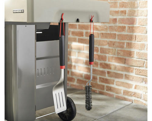 Grillverktyg och grillborste hänger på en grill.