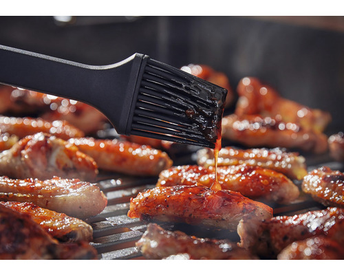 Grillborste som penslar kött på en grill