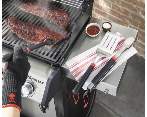 Tillagning av kött på en grill med grillverktyg, marinad och grillhandske
