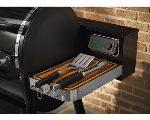 Detaljvy av en Weber SmokeFire grill med grillverktyg och digital styrning.