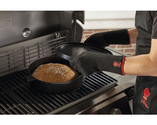 Brödbakning i en holländsk ugn på grillen med grillhandskar och förkläde