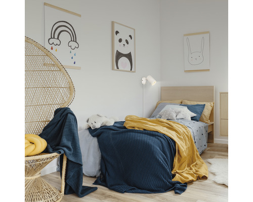 Ljust barnrum med säng, rottingfåtölj och dekorativa väggmålningar.