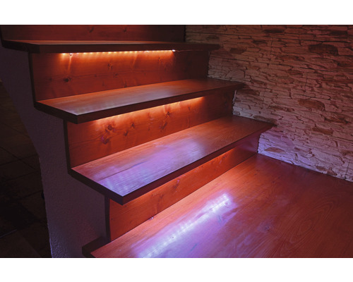 Trätrappa med indirekt belysning och stenmur