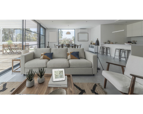 Ljust vardagsrum med soffa, fåtöljer, matbord och digital termometer på ett soffbord