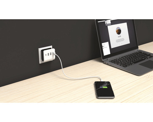 Grenuttag med USB-portar, laptop och smartphone på ett skrivbord