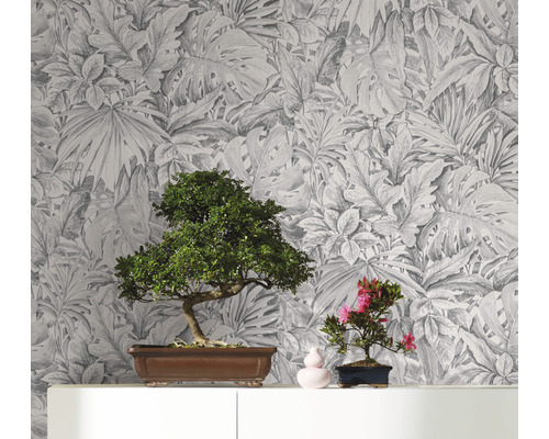Dekorativ tapet med botaniskt bladmönster som bakgrund för två bonsaiplantor på en hylla