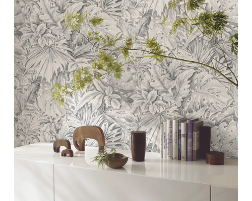 Dekorativt rum med en tapet med tropiska växtmotiv bakom ett vitt skåp