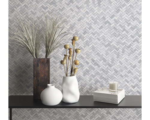 Dekorativa vaser och en stapel böcker på en hylla framför en mosaikvägg