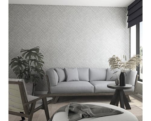 Ljust vardagsrum med mönstrad tapet, soffa, fåtölj och dekorativa element