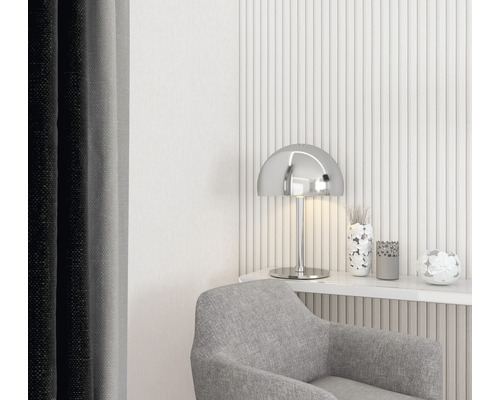 Dekorativt vardagsrum med grå fåtölj, silverlampa och blommiga accenter