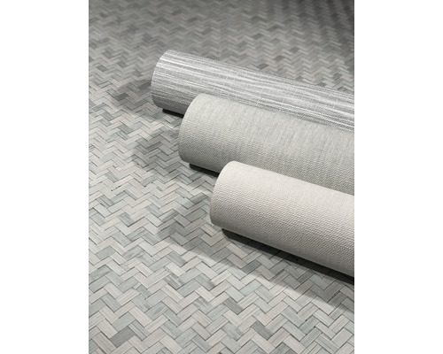 Tre rullar textil tapet på ett golv med fiskbensmönster.