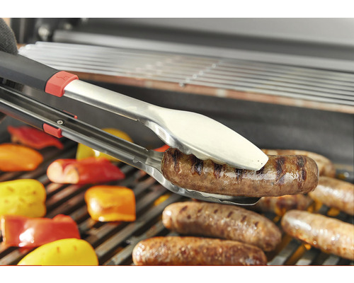 Grilltång håller korv över grillgaller