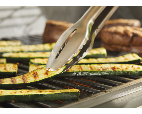 Grilltång vänder zucchini på grillen