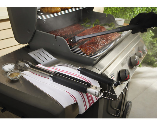 Grillscen med revbensspjäll, grilltång, stekspade, pensel och kryddor på en grill