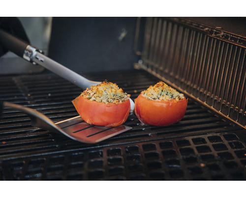 Två fyllda tomater på en grill med stekspade.