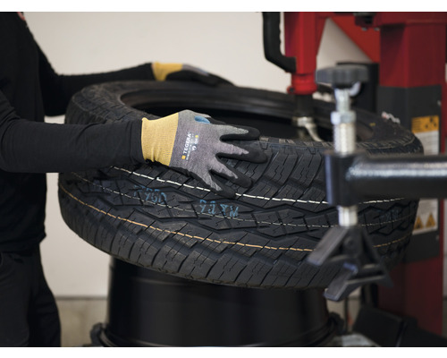 En person monterar med handskar ett däck på en däckmonteringsmaskin.