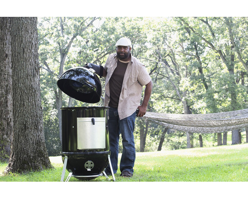 Man öppnar en rund grill i trädgården.