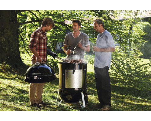 Tre män grillar utomhus med en kolgrill.