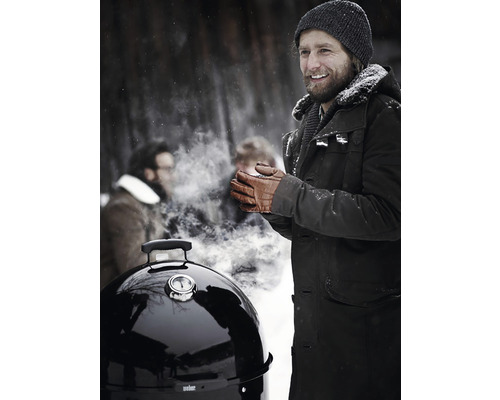 Scen med en man som står utomhus vid en grill på vintern