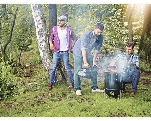 Utomhusgrillscen med tre män som grillar i skogen.