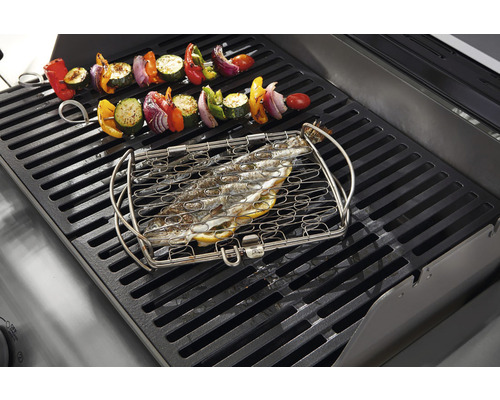 Fisk i fiskgrillkorg och grönsaksspett på en grill