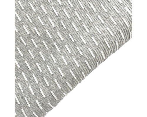 Detaljvy av en grå matta med vita dekorationssömmar