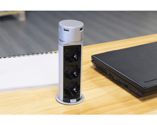 Infälld uttagslist med tre uttag och USB-portar på ett skrivbord