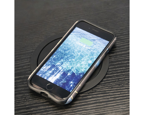 En smarttelefon med skyddsfodral ligger på en trådlös laddare.
