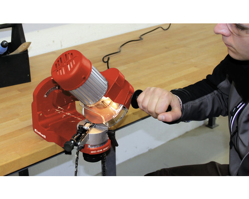 En man slipar en motorsåg med en motorsågslipmaskin av märket Einhell.