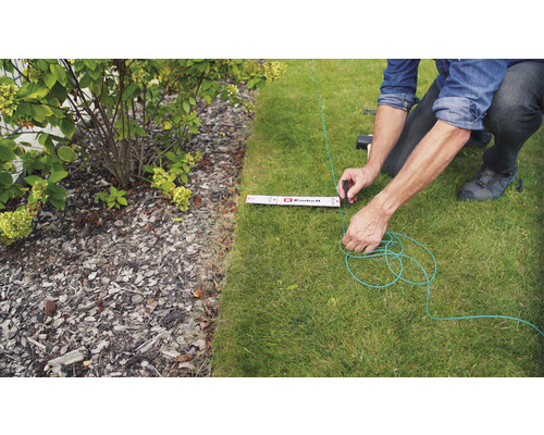 Trädgårdsarbete: Man spänner ett grönt riktningssnöre med tumstock