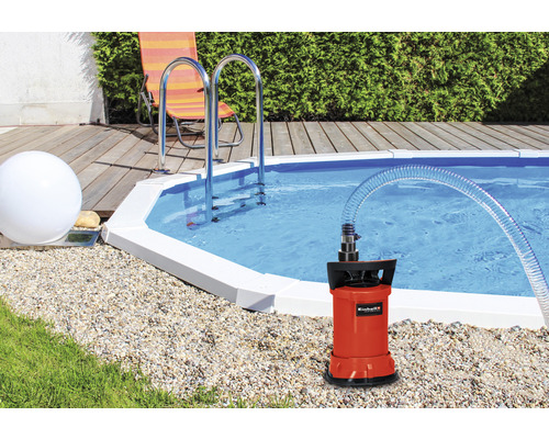 Dränkbar pump bredvid pool med stege och trädgårdsdesign