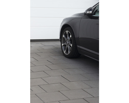 Scen med stenläggning och bil framför ett garage