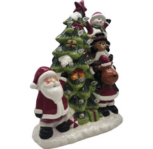 Juldekoration med jultomte, snögubbe, teddybjörn och ren bredvid en julgran med ljus