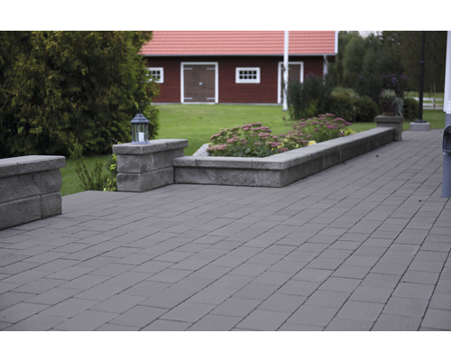 Stensatt område med blomsterrabatt och hus i bakgrunden