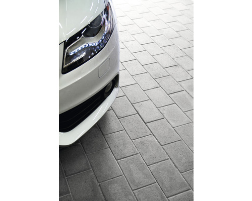 Närbild av en stenlagd yta bredvid en bil.