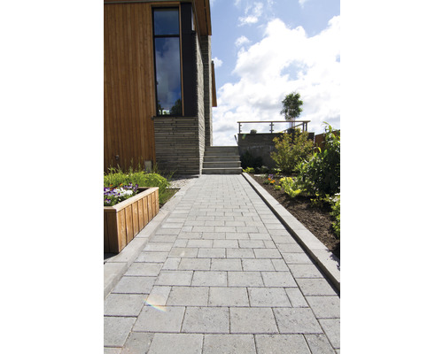 Exteriörbild av ett hus med en stenlagd gångväg, stentrappor och rabatter.