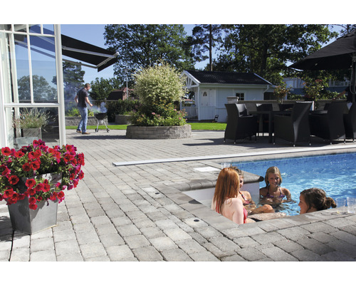 Terrass med stenläggning, pool och sittgrupp i trädgården